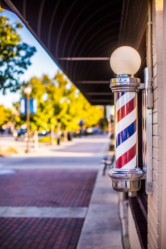 Classic barber pole on a vibrant city street under a sunny sky.